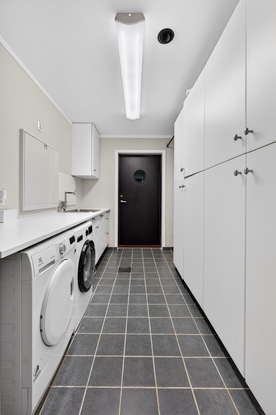 Vaskerommet er praktisk plassert like innenfor hallen, med direkte adkomst både fra den integrerte garasjen og fra baksiden av huset hvor det er etablert en platting. God løsning for håndtering av vått og skittent yttertøy, samt for tørking av klær. Galleribilde