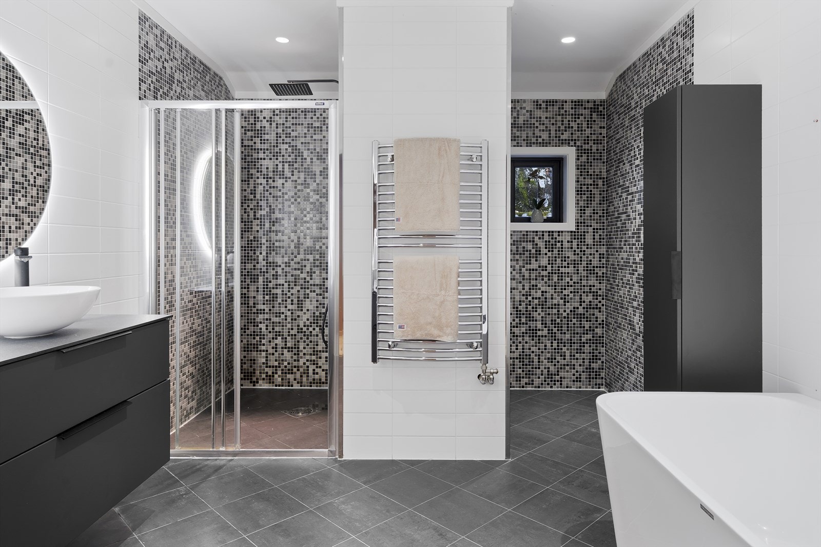 Badet er helfliset i nøytrale farger, men med innslag av mosaikkfliser som gir en fin kontrast Galleribilde