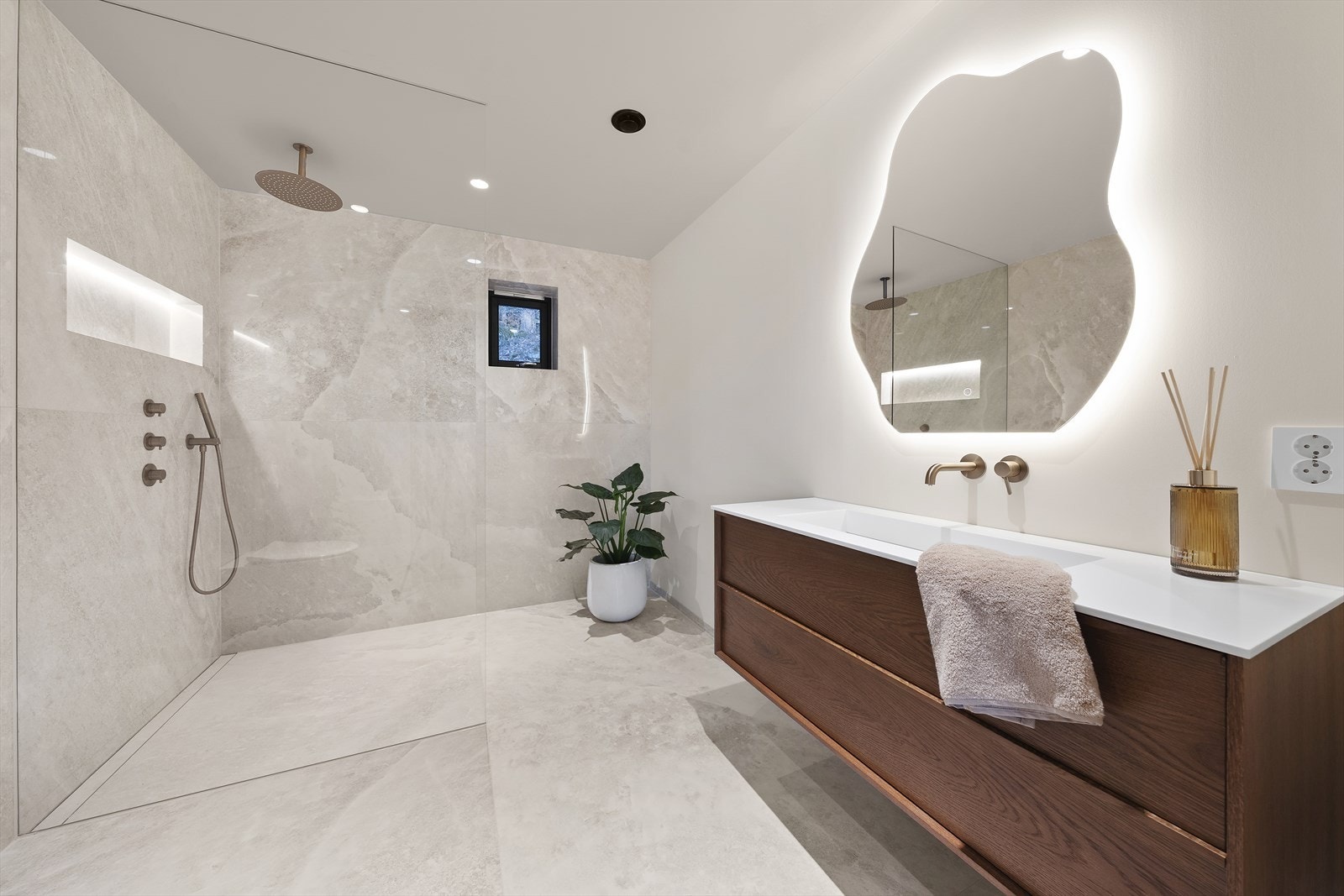 Dusjhjørnet er adskilt med glassvegg og utstyrt med integrert armatur, takdusj og innfelt belyst hylle Galleribilde