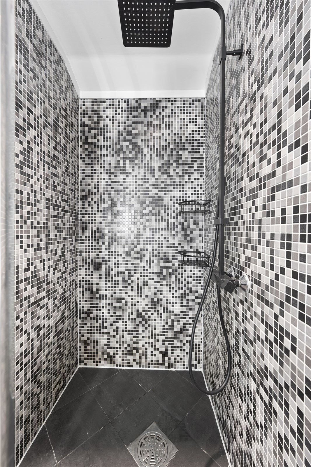 Dusjnisjen er avdelt med skyvedør i glass og er utstyrt med takdusj, samt vegghyller Galleribilde