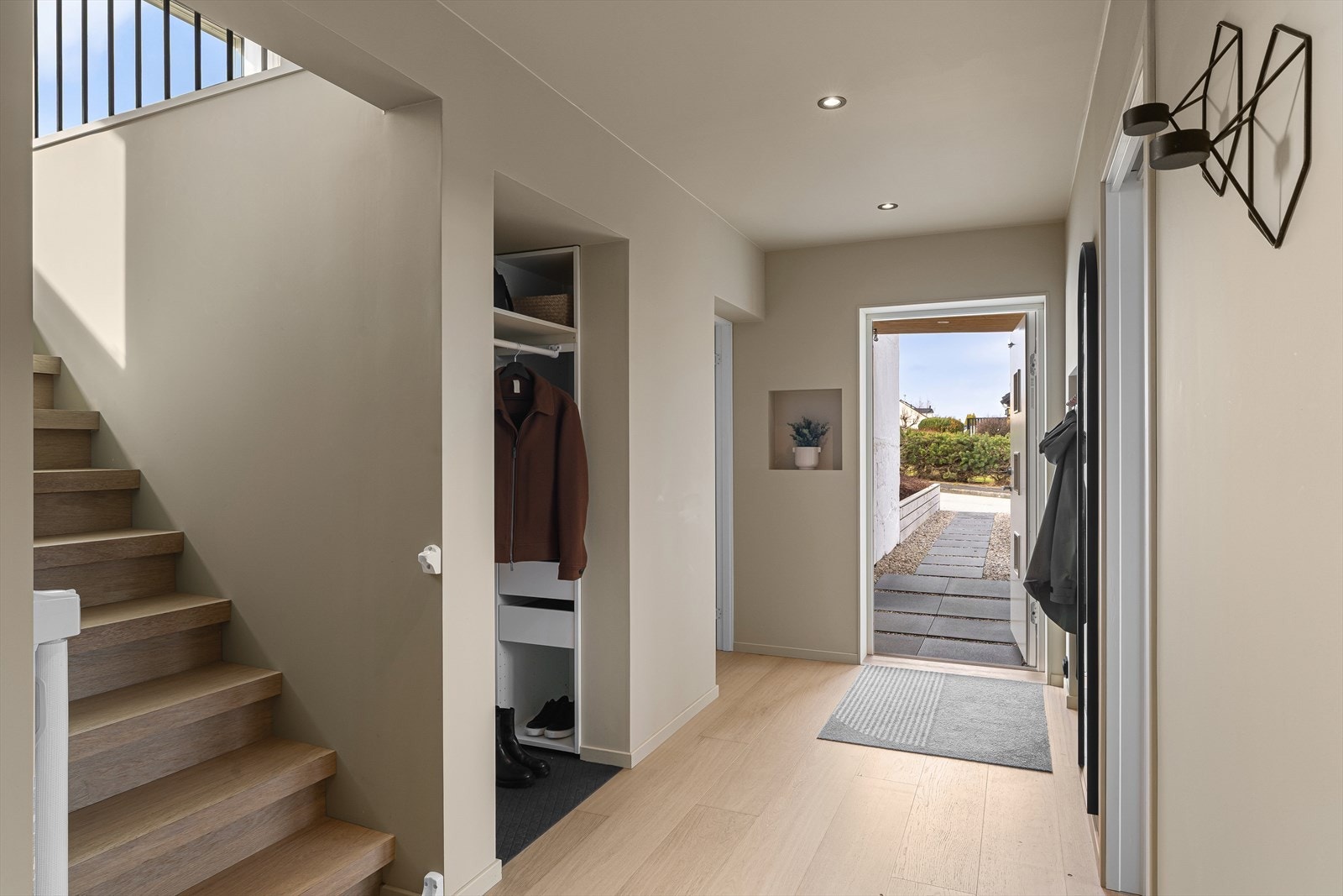 Lys og innbydende entré med et praktisk innhuk for yttertøy og sko Galleribilde