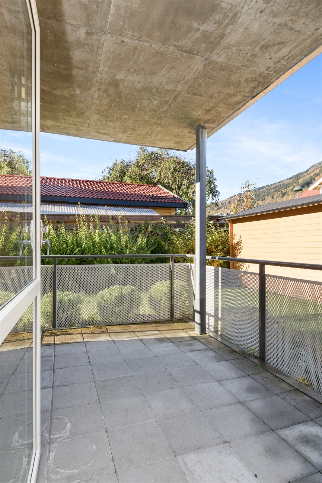 Frå stova er det utgang til overbygd terrasse med betongheller og rekkverk i stål. Galleribilde