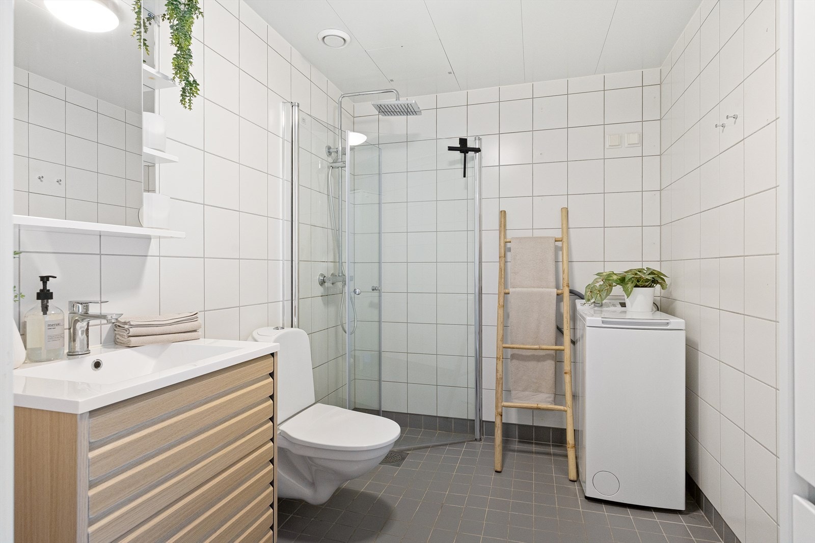 Romslig, tidløst baderom med flislagte overflater og elektriske varmekabler. Det er opplegg for vaskemaskin. Galleribilde