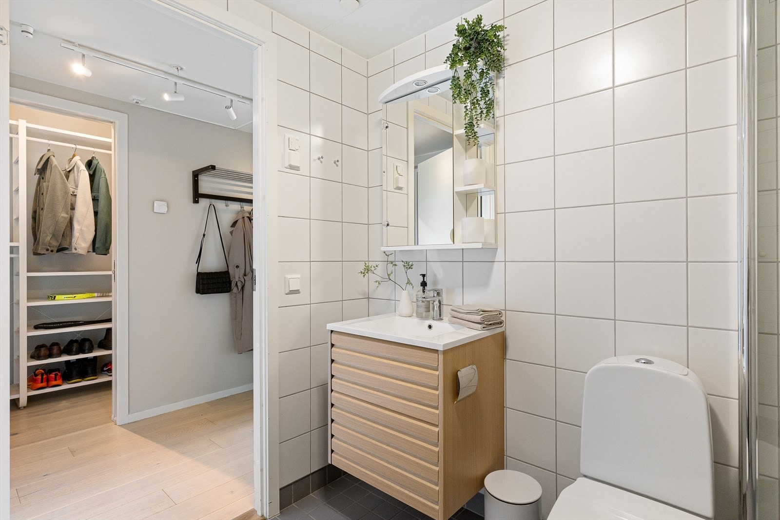 Rommet har sanitærutstyr som består av veggmontert toalett med utenpåliggende sisterne, dusjhjørne vegg/dør i herdet glass og baderomsinnredning med skap, servant og vegghengt speilskap med belysning. Galleribilde