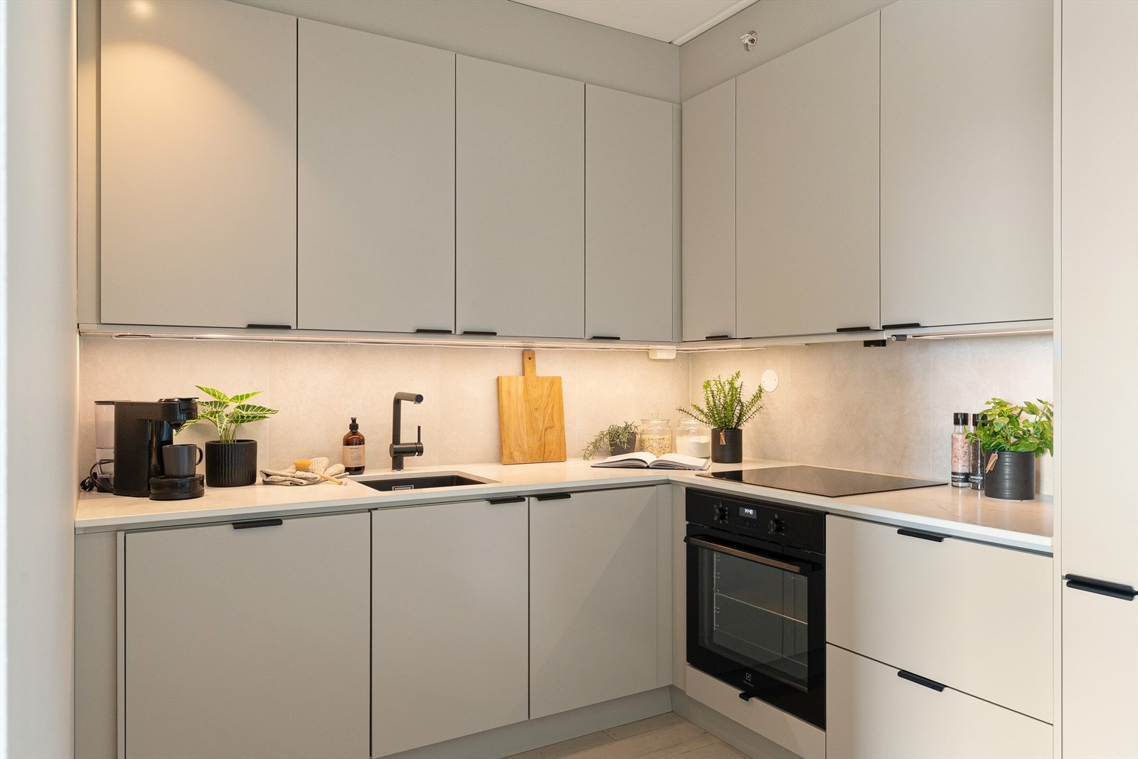 Moderne kjøkkeninnredning fra 2025 med slette fronter, slitesterk benkeplate i keramikk og storformat fliser som backsplash over kjøkkenbenken. Galleribilde