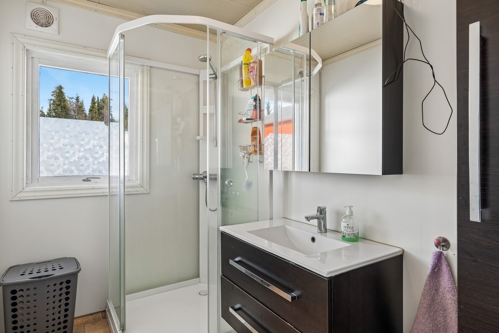 Badet i hovedetasjen har baderomsplater på veggene og et dusjkabinett som ble skiftet i 2021. Galleribilde