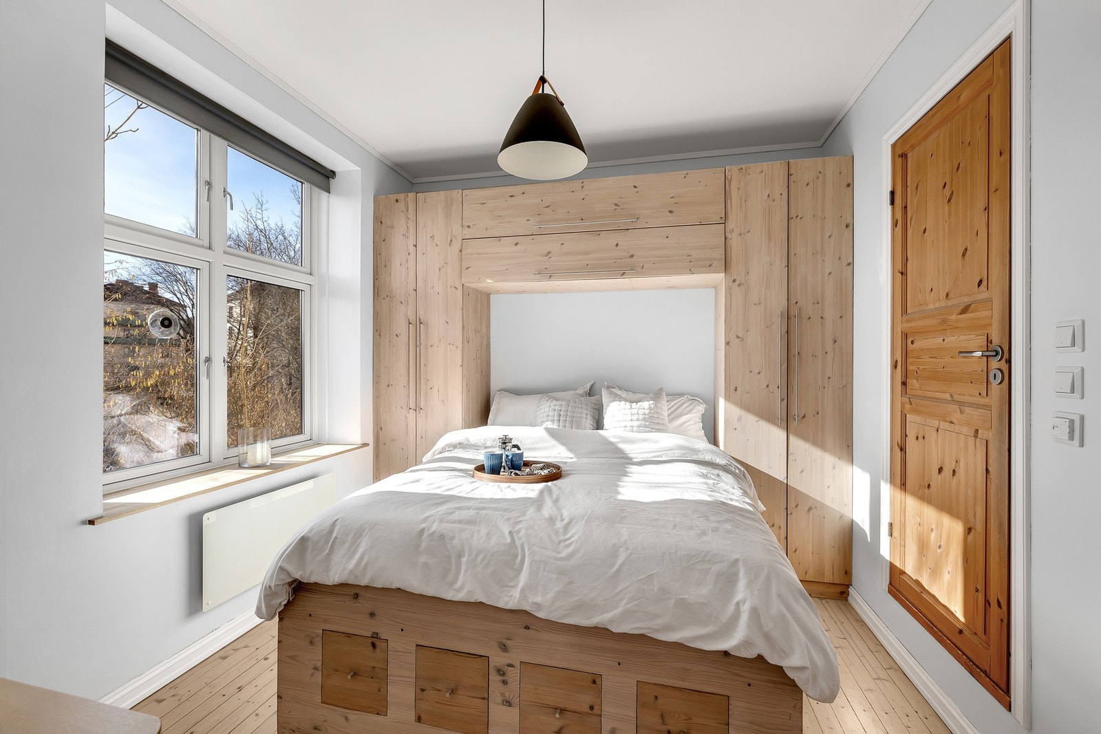 Lyst og rolig soverom med plassbygget seng og tilhørende garderobeløsning. Galleribilde