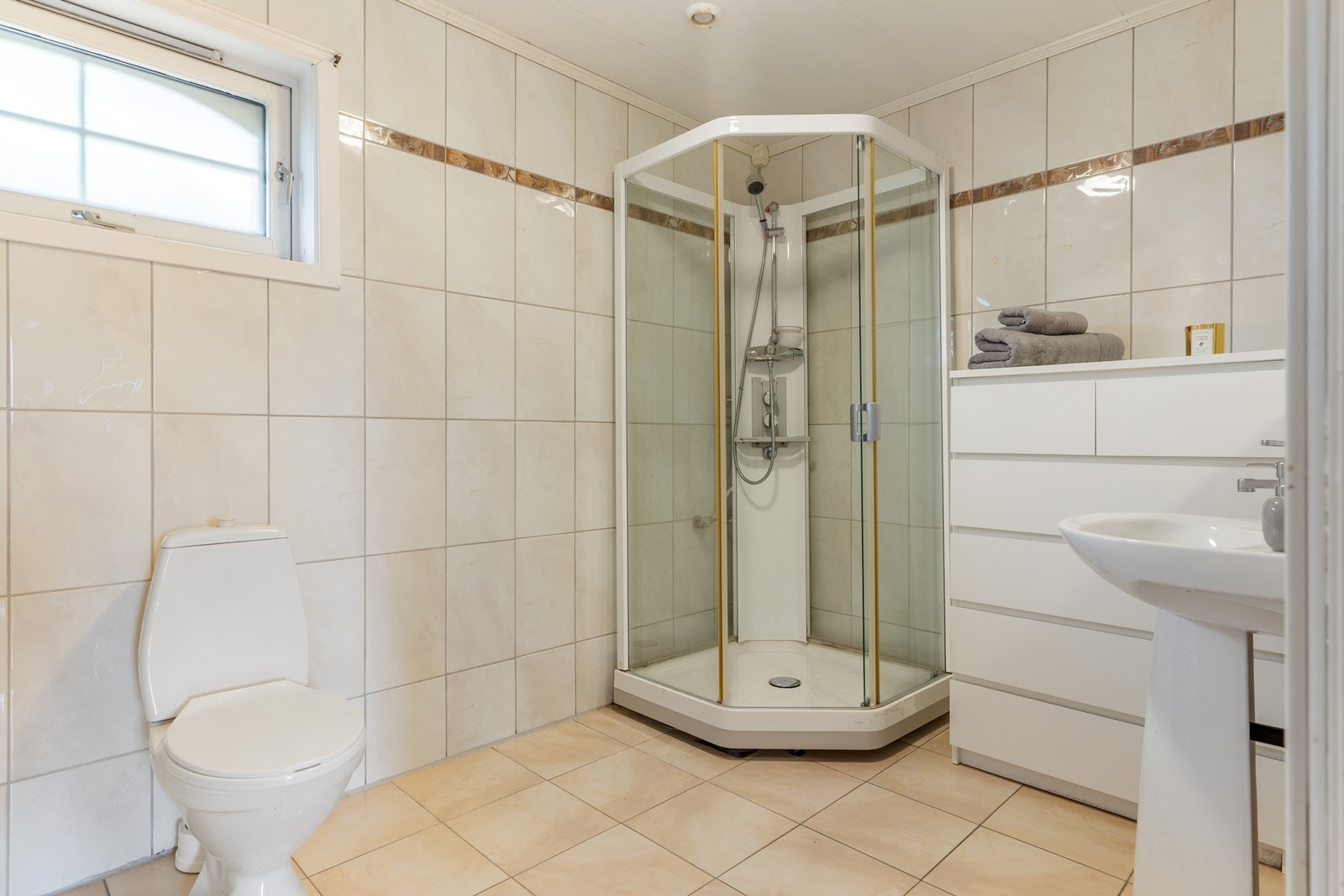 Stort helfliset bad med varmekabler i gulv. Badet har dusjkabinett, servant og toalett. Galleribilde