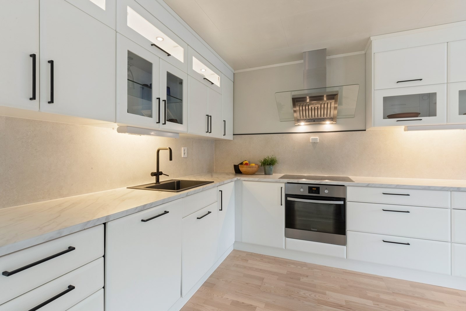 Hvit innredning med slett fronter. Kjøkkenet er innredet med kjøle/fryseskap, oppvaskmaskin, stekeovn og induksjonstopp. Galleribilde