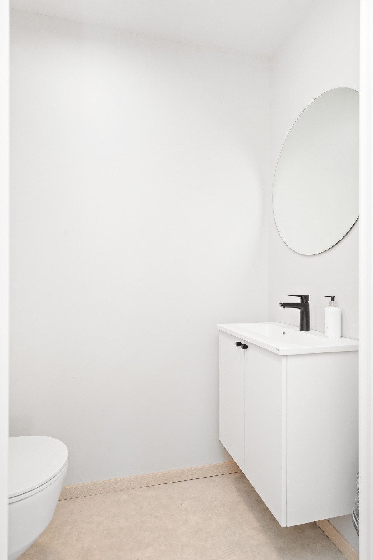 Lyst toalett med servantskap, speil og veggehengt toalett. Galleribilde