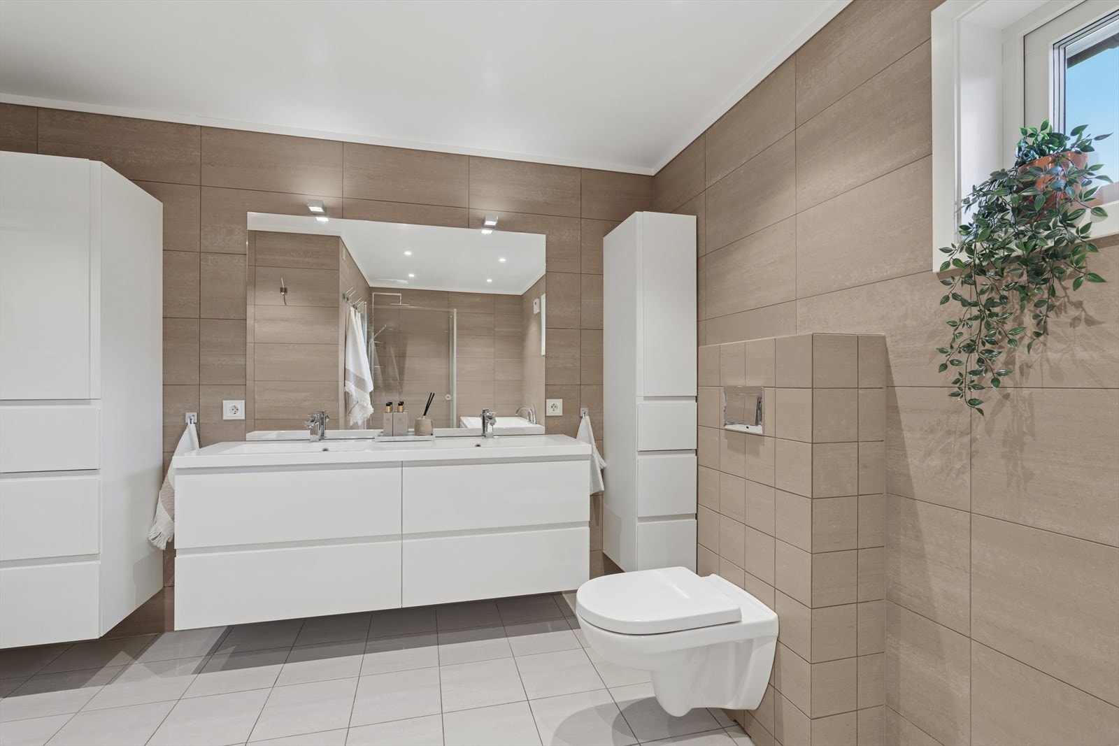 Badet er ellers utstyrt med dusjhjørne, badekar, vegghengt toalett og baderomsinnredning med servant som gir rikelig med lagringsplass. Galleribilde