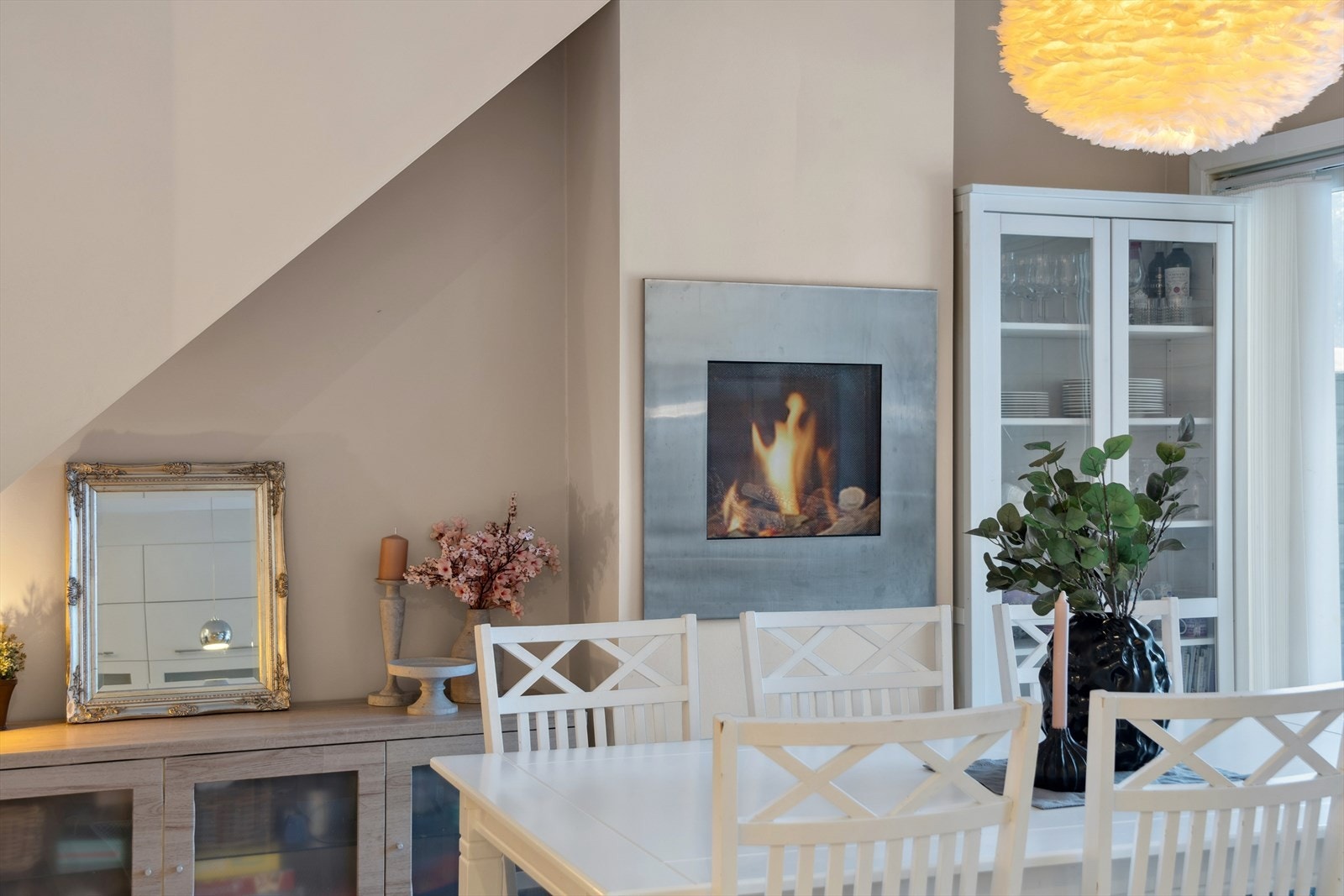 Stuen har en stilfull og dekorativ gasspeis som skaper en lun og behagelig atmosfære. Peisen gir både varme og et flott visuelt uttrykk, og bidrar til økt hygge i oppholdsrommet - perfekt for kjølige kvelder og en ekstra dose komfort i hverdagen. Galleribilde