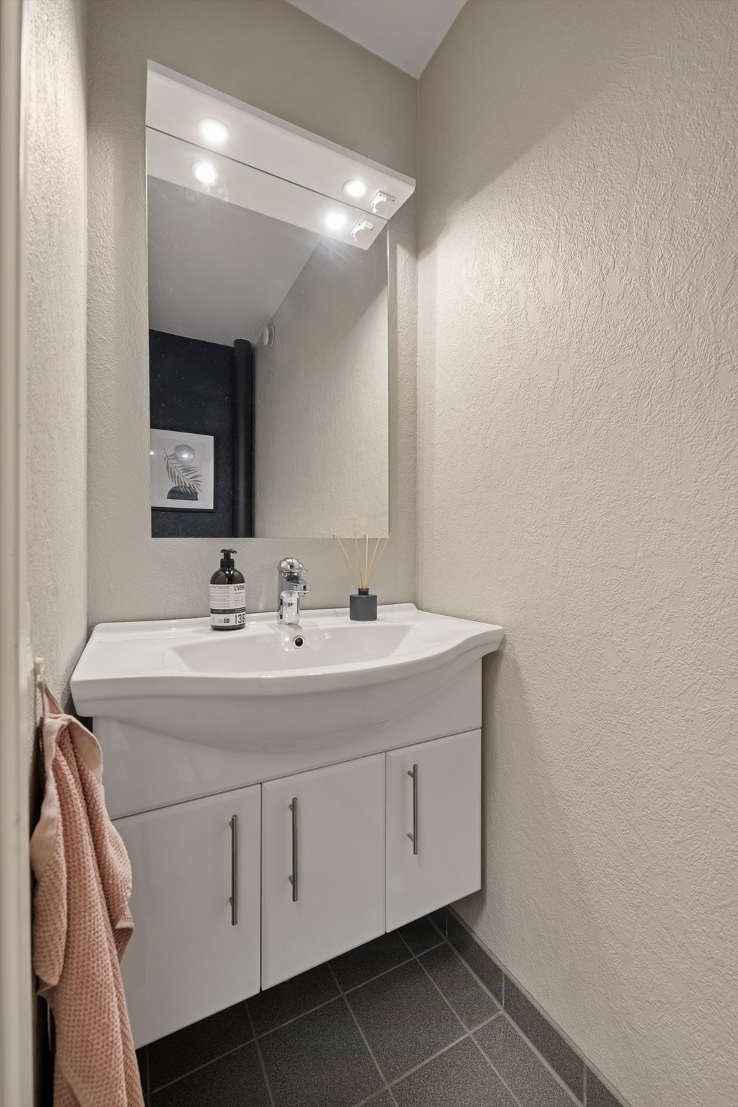 Toalettrommet har flislagt gulv, malt vegg og servant med praktisk underskap. Galleribilde