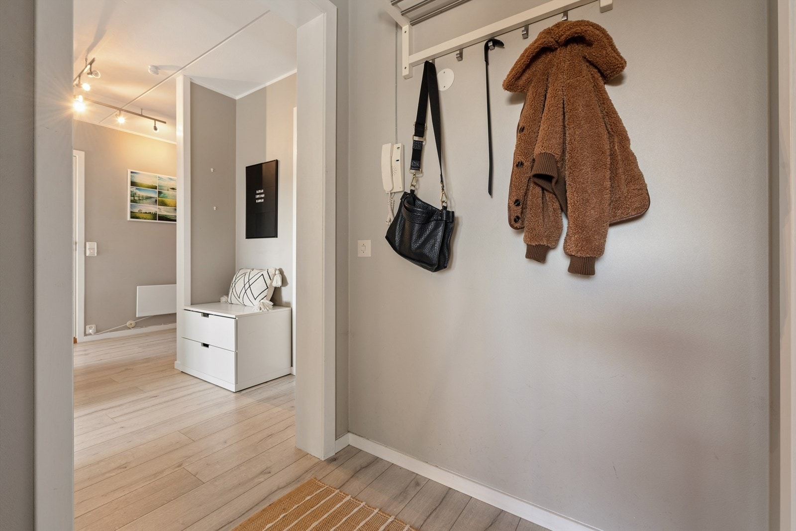 Entréen har malte vegger og et praktisk oppheng for yttertøy. Galleribilde