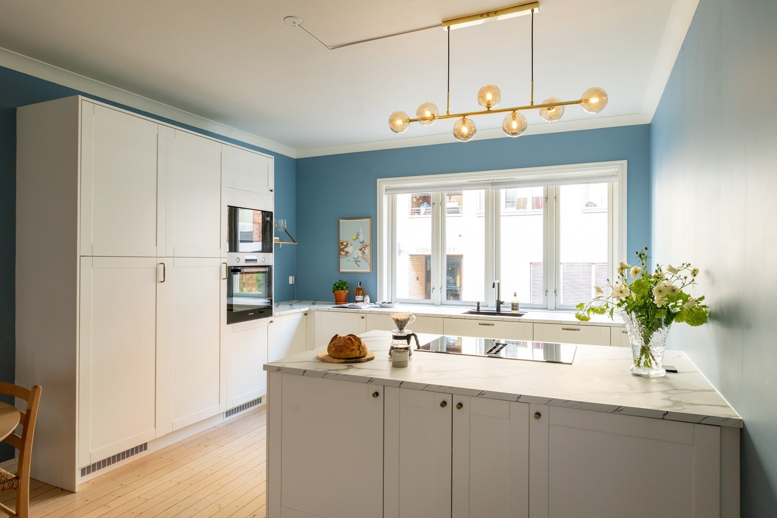 Moderne kjøkken med kjøkkenøy, rikelig med skapplass og store vindusflater som slipper inn godt med dagslys Galleribilde