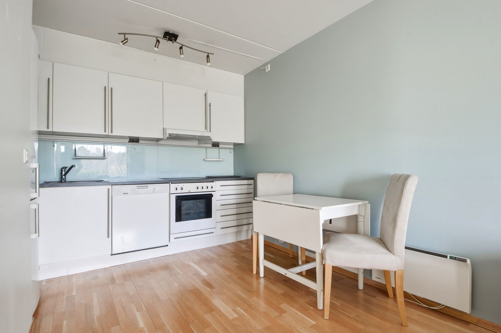 Kjøkkenet har en funksjonell og praktisk utforming, og innredning består av hvite, glatte fronter og laminert benkeplate. Galleribilde