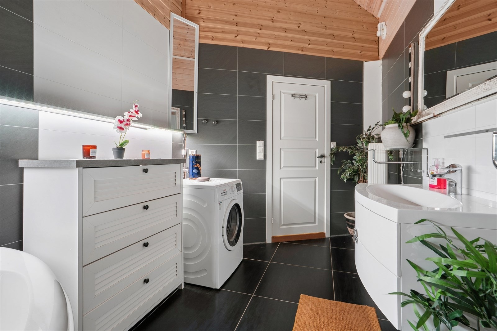 Badet er innredet med servant, skapinnredning, speil, lysarmatur, badekar, vegghengt toalett og opplegg for vaskemaskin. Galleribilde