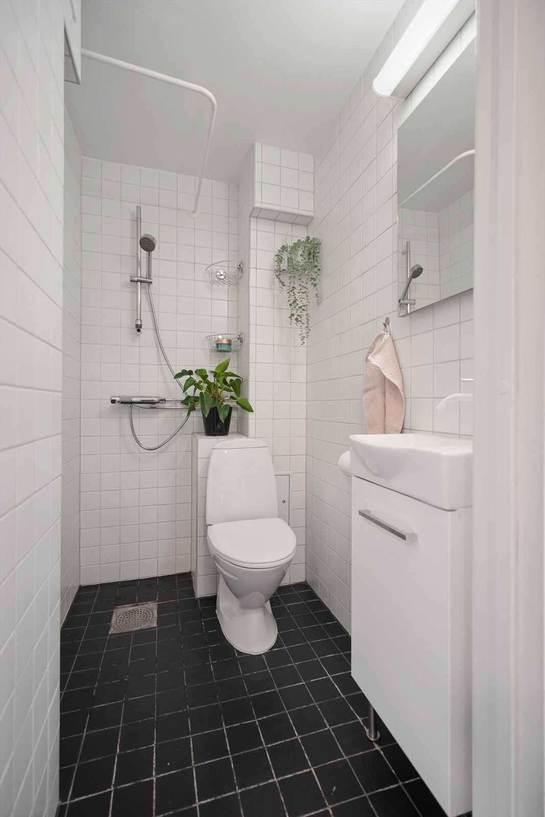 Badet er utstyrt med dusjhjørne, servant med underskap og toalett. Galleribilde