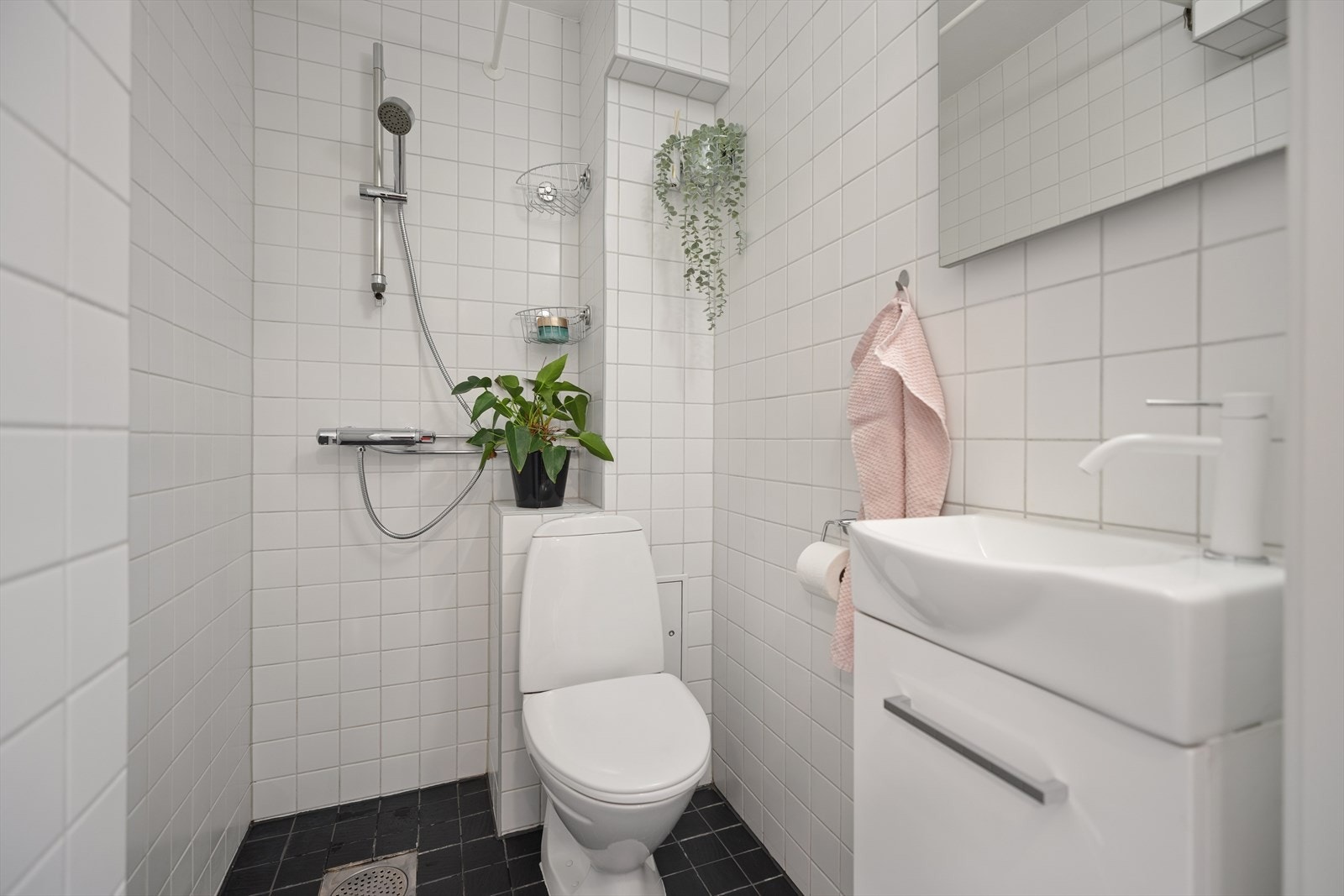 Flislagt bad med lyse fliser på vegger og mørke gulv. Galleribilde