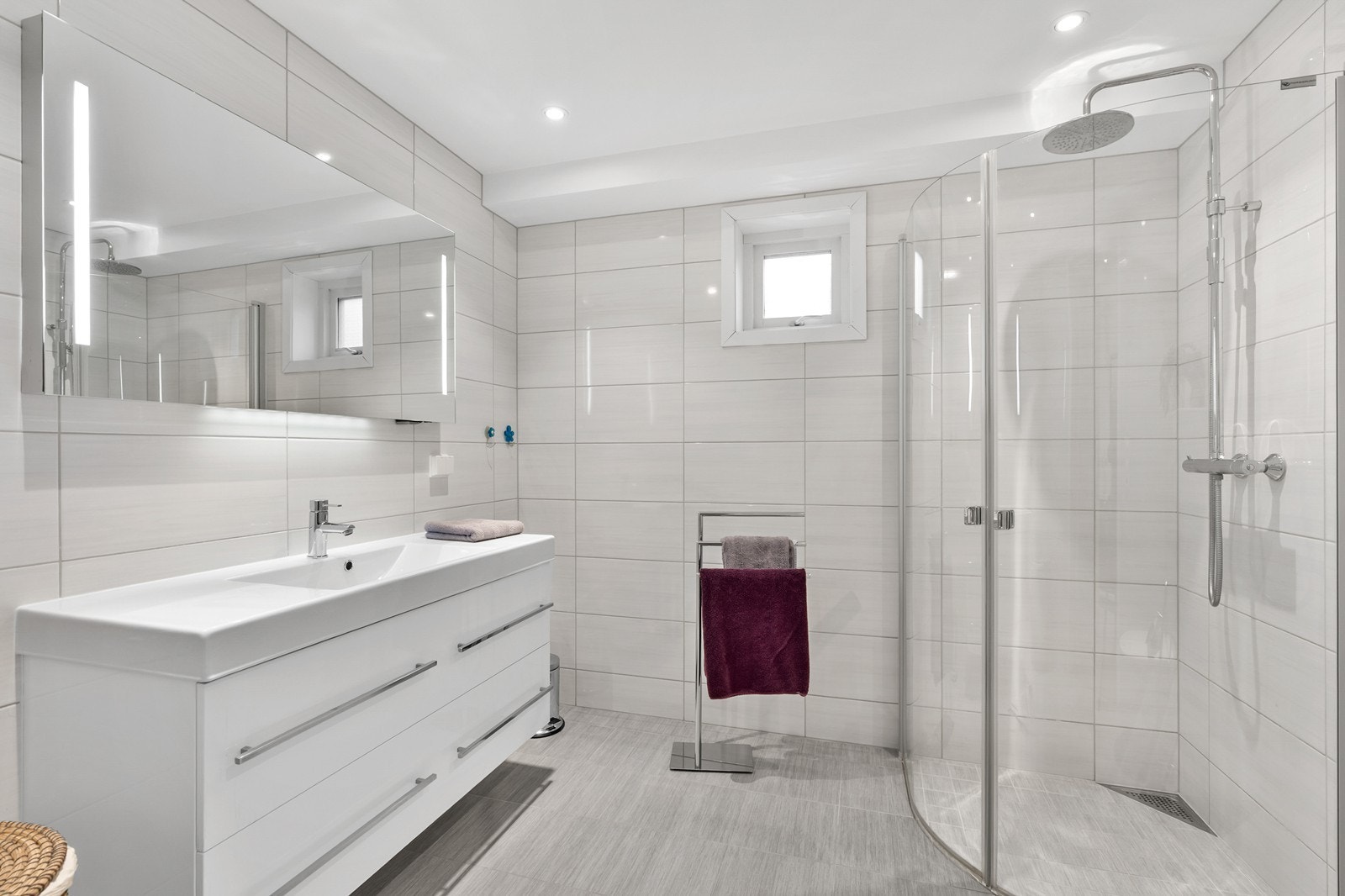 Badet er romslig og innredet med servant med praktisk skuffeløsning, vegghengt toalett og dusjløsning med glassdører Galleribilde