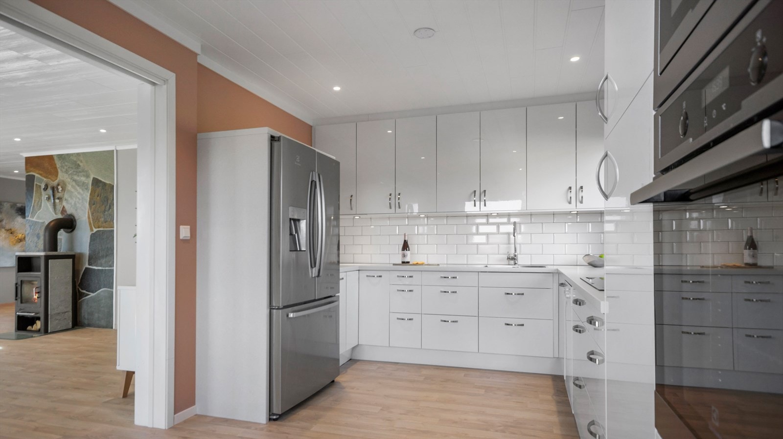 Kjøkkeninnredning består av slette og glatte fronter i hvit høyglans, og er utstyrt integrert komfyr og mikrobølgeovn i høyskap, samt innfelt oppvaskmaskin og frittstående side-by-side kjøleskap som medfølger. Galleribilde