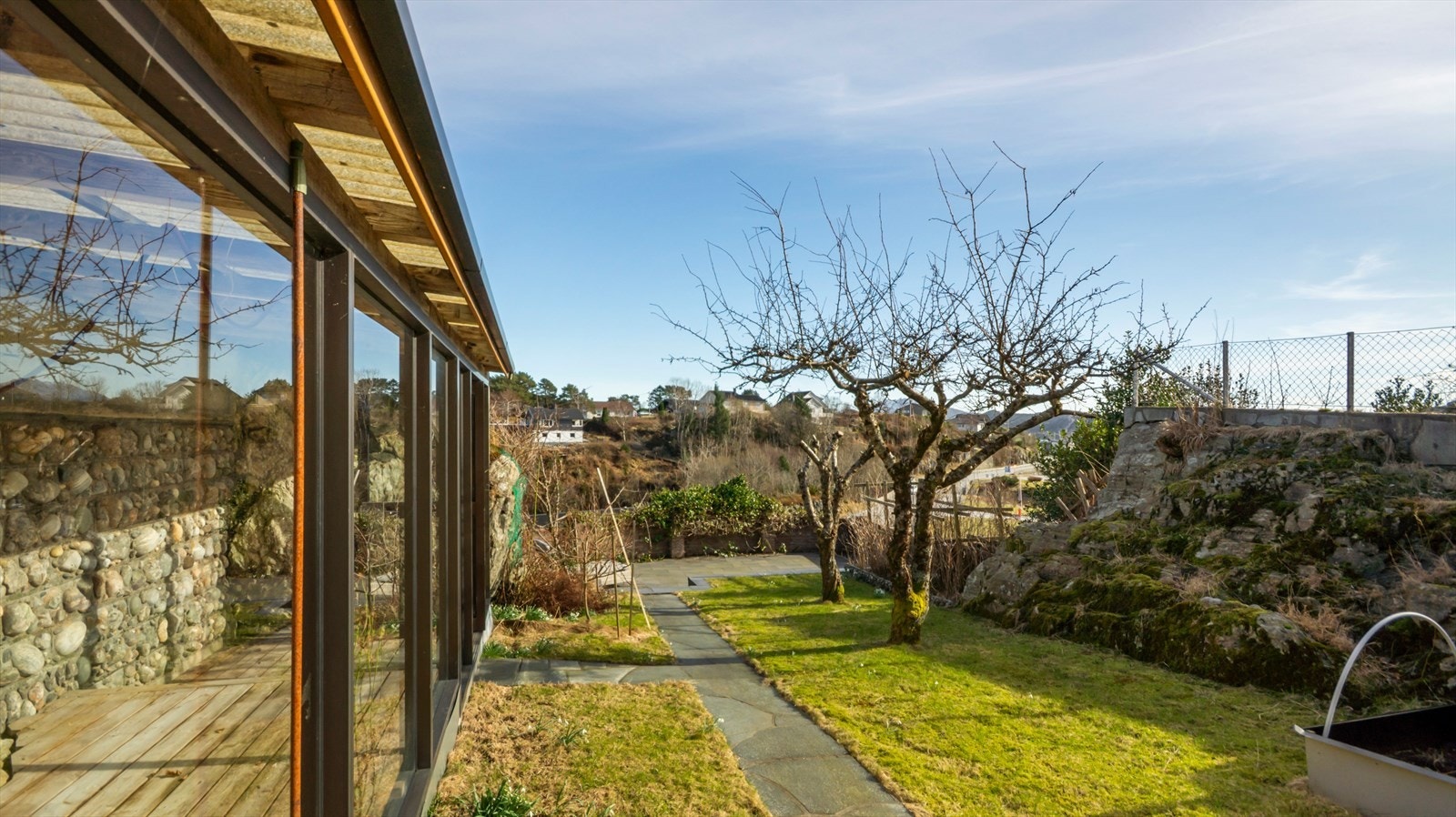 Drivhus består av terrassebord som gulvdekke og overflate vegger bestående av vindusflater, samt er deler av veggen bygget sammen med berget. Det er trukket hageslage frem til bygningen. Galleribilde