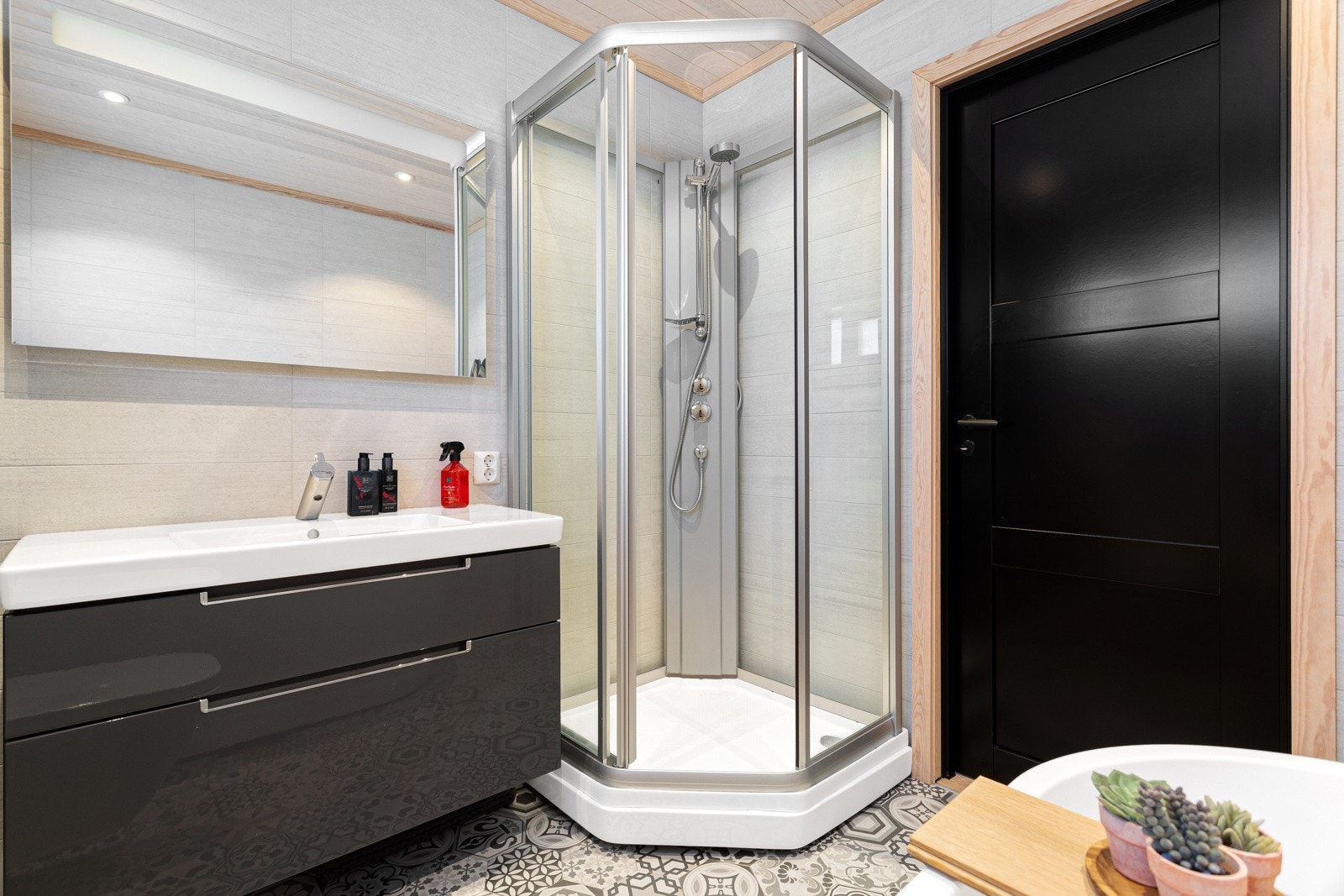 Badet har hel servantplate over skuffeinnredning, speil med integrert lys, badekar, dusjkabinett og vegghengt toalett. Galleribilde