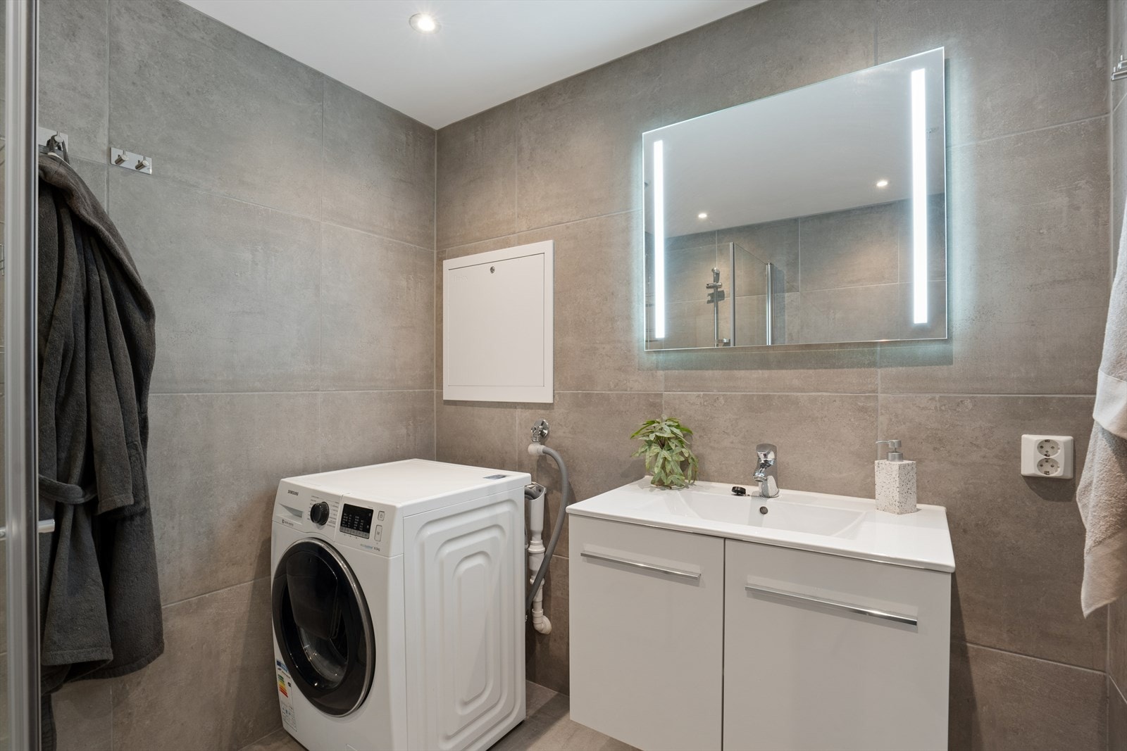 Badet er utstyrt med servantskap med skuffer, speil med belysning, vegghengt toalett og dusjhjørne med glassvegger. Galleribilde