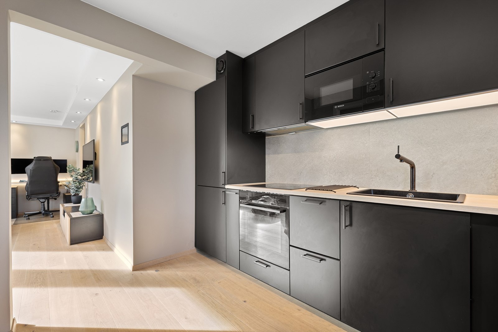 Kjøkkenet på 7,5m² byr på rikelig med både skap- og benkeplass i lekre, sorte detaljer. Galleribilde