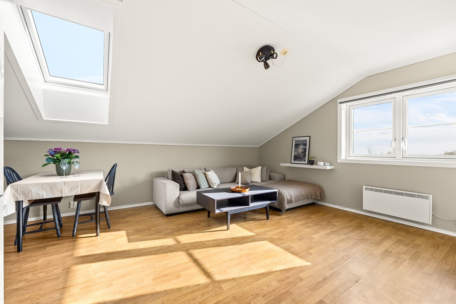 Stuen er åpen og lys med parkett på gulv og slette vegger malt i en dus og lun fargetone. Galleribilde