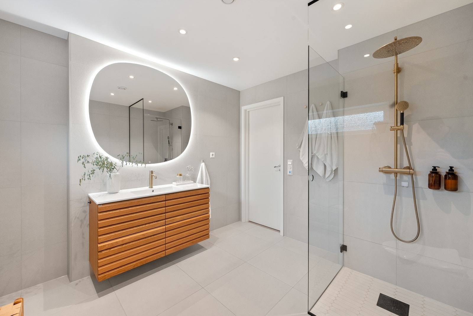 Rommet er innredet med en baderomsinnredning fra Linn Bad med heldekkende servant og speil, et veggmontert toalett og et dusjhjørne med rett, innsvingbar glassdør. Galleribilde