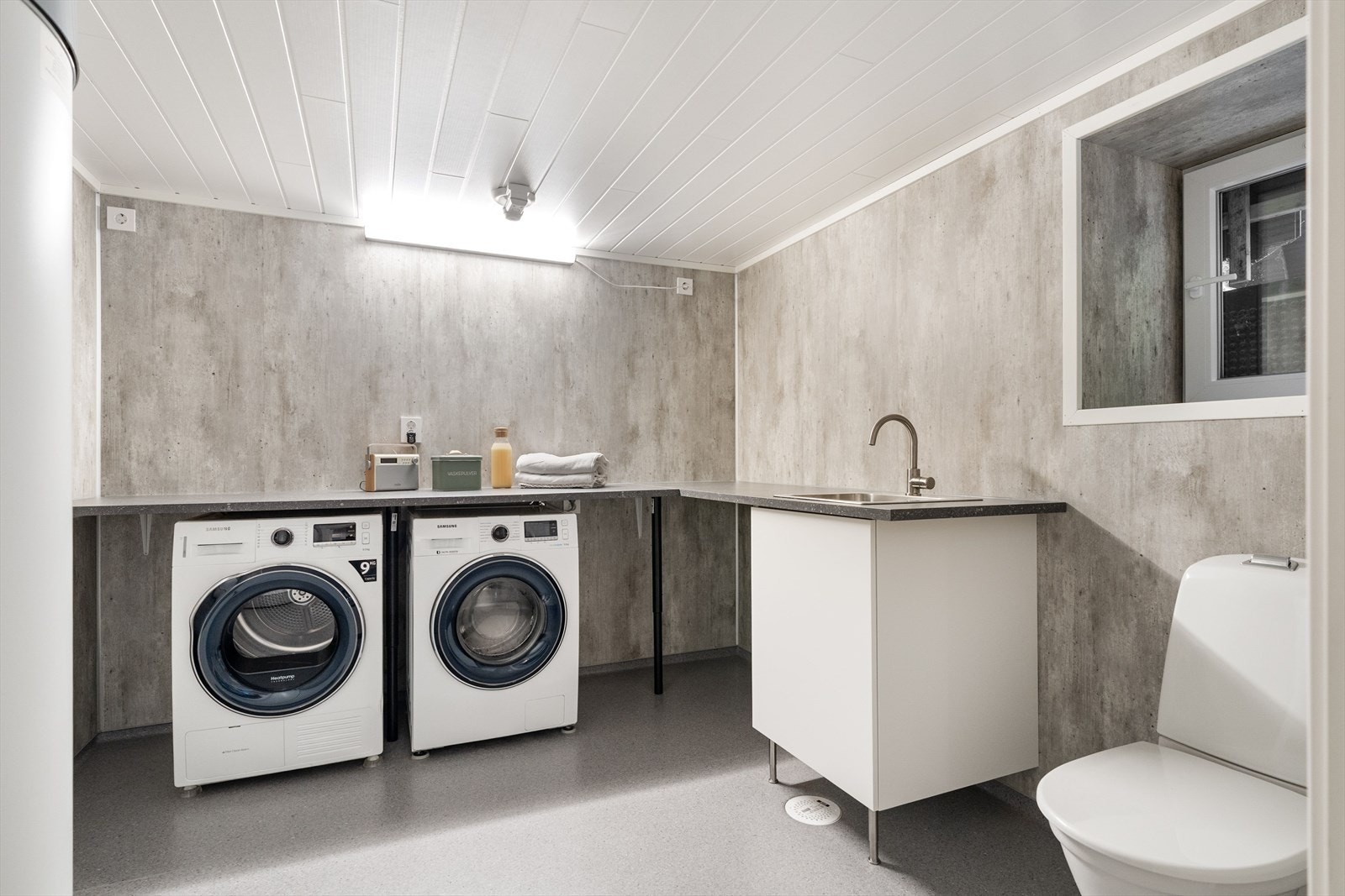 Vaskerommet byr på rikelig med benkeplass, utslagsvask, klosett. Rommet er ellers utstyrt med sluk og stor varmtvannsbereder. Galleribilde