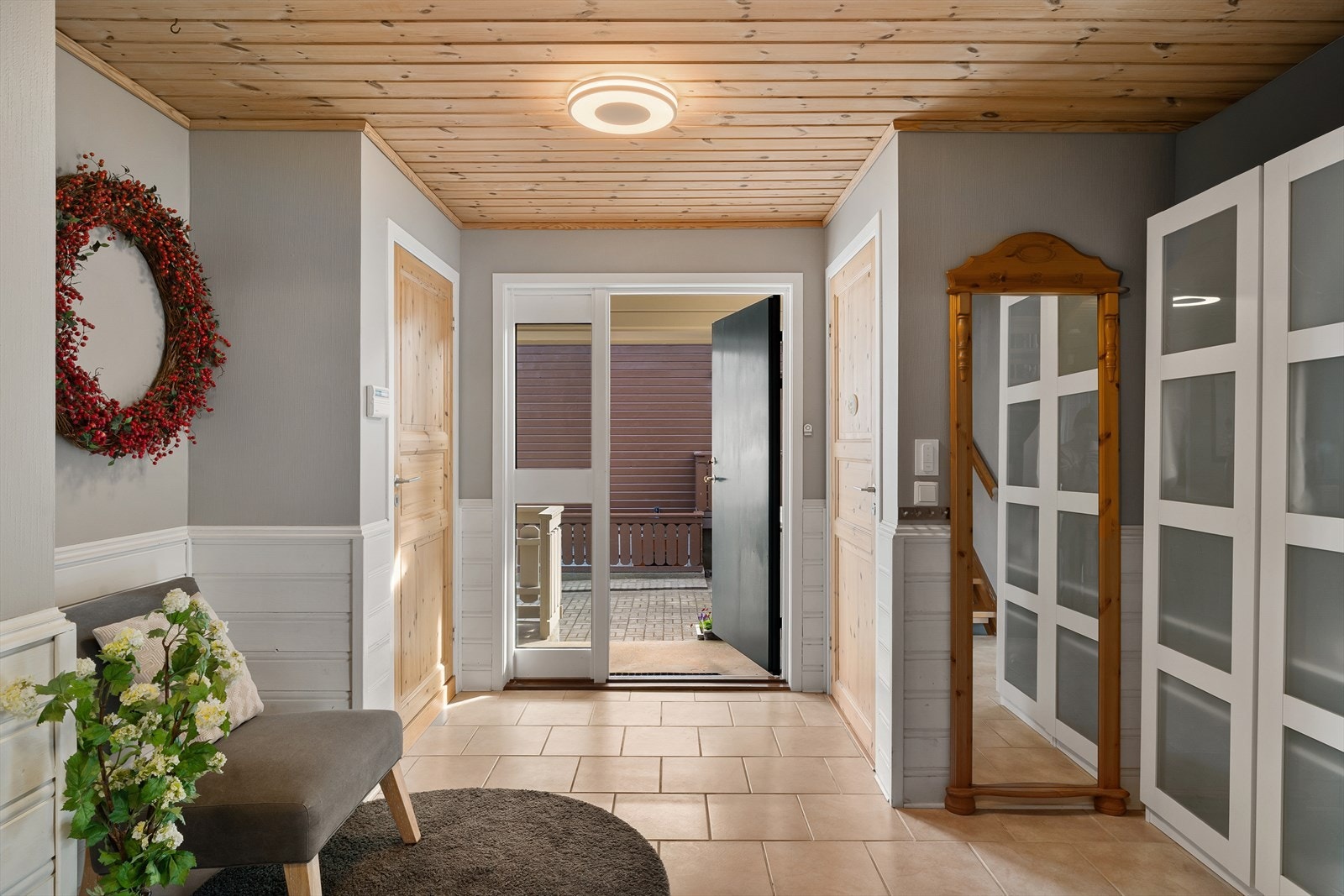 Innbydende og romslig entré og hall med fliser på gulv og god garderobeplass Galleribilde