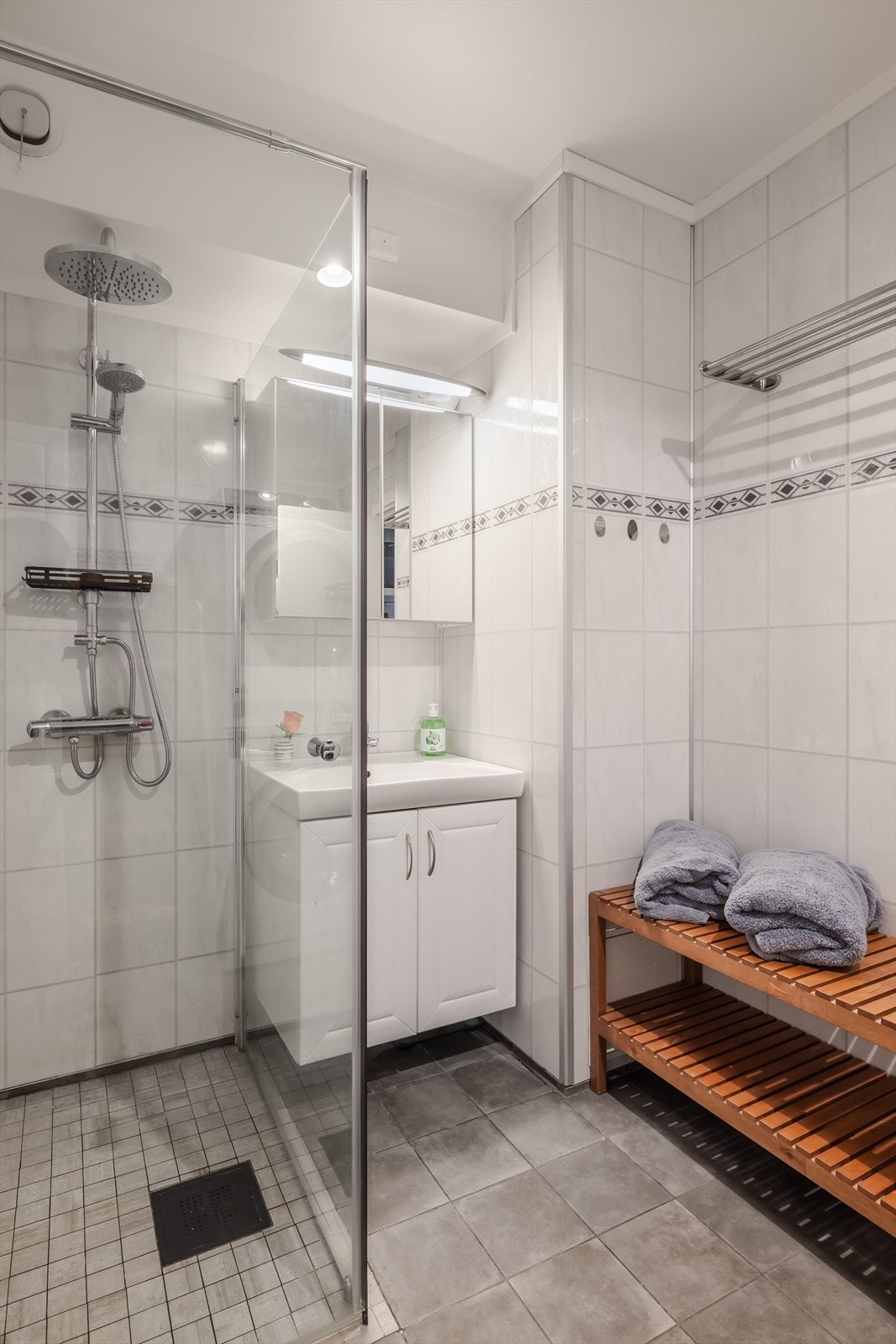 Rommet er utstyrt med dusjhjørne med innfellbare dusjdører og vegghengt dusjbatteri med regnfall. Baderomsinnredning med underskap med heldekkende servant. I overkant av servanten er det speilskap med lys. Galleribilde