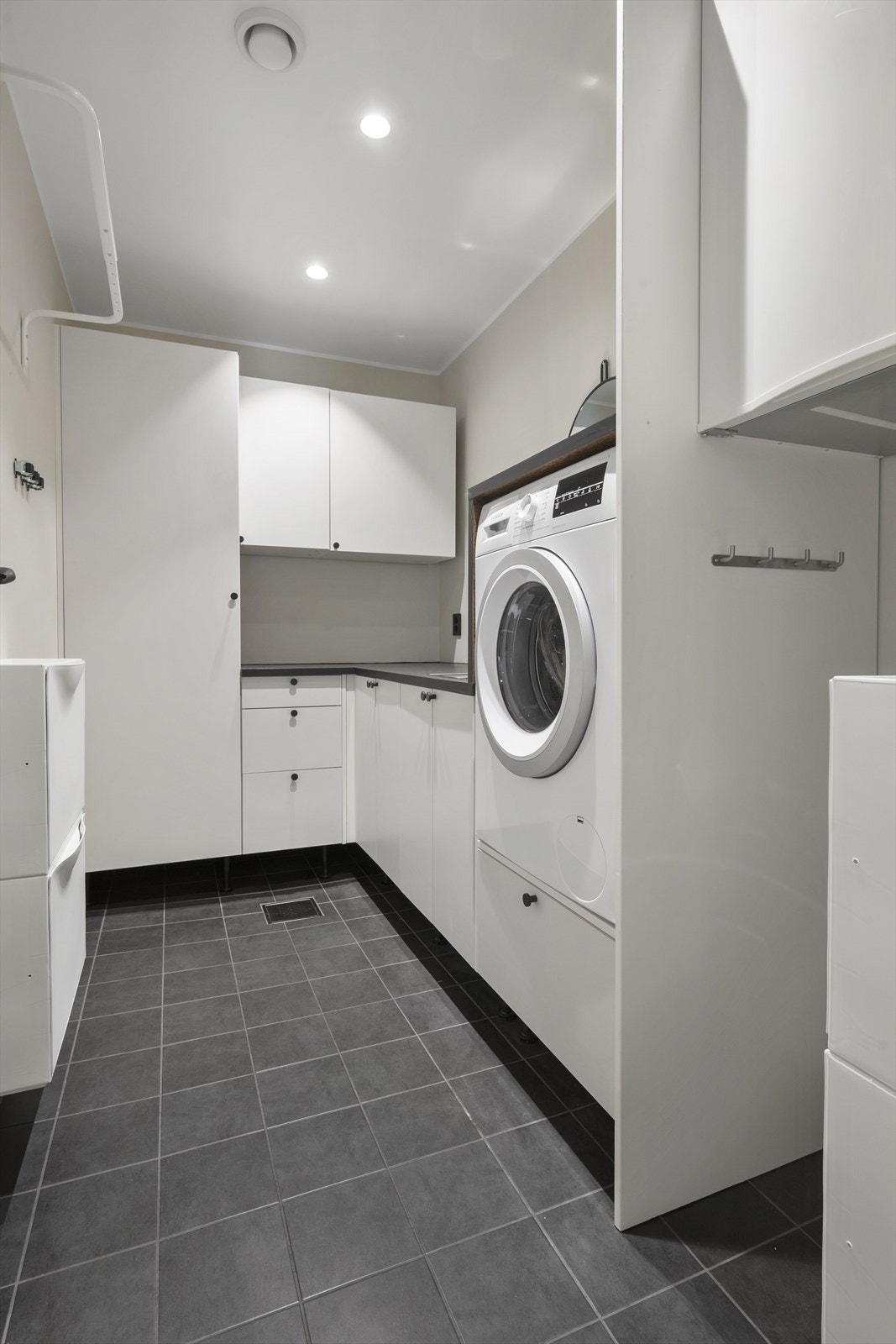 Vaskerommet har flislagt gulv med vannbåren varme, og har innredning med god skapplass, benkeplate, skyllekar, opplegg for vaskemaskin, og mulighet for installering av tørketrommel. Galleribilde