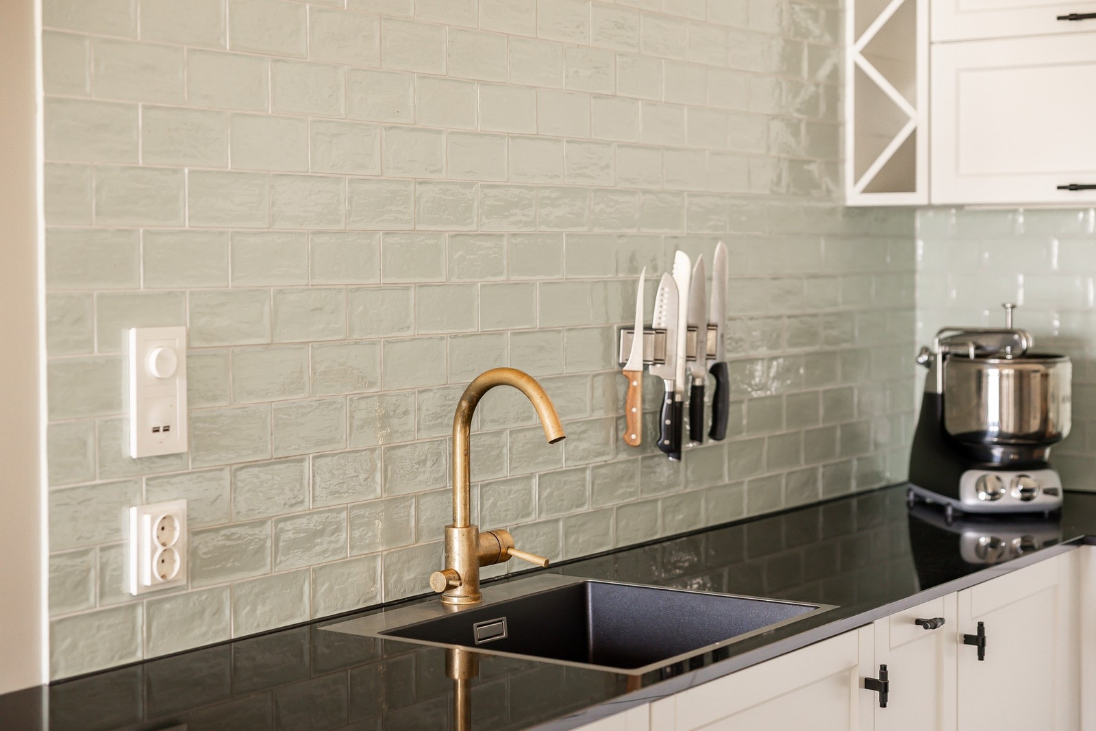 Innredningen har lyse, profilerte fronter kombinert med mørk benkeplate og flislagt backsplash, noe som gir et moderne og stilrent uttrykk. Galleribilde