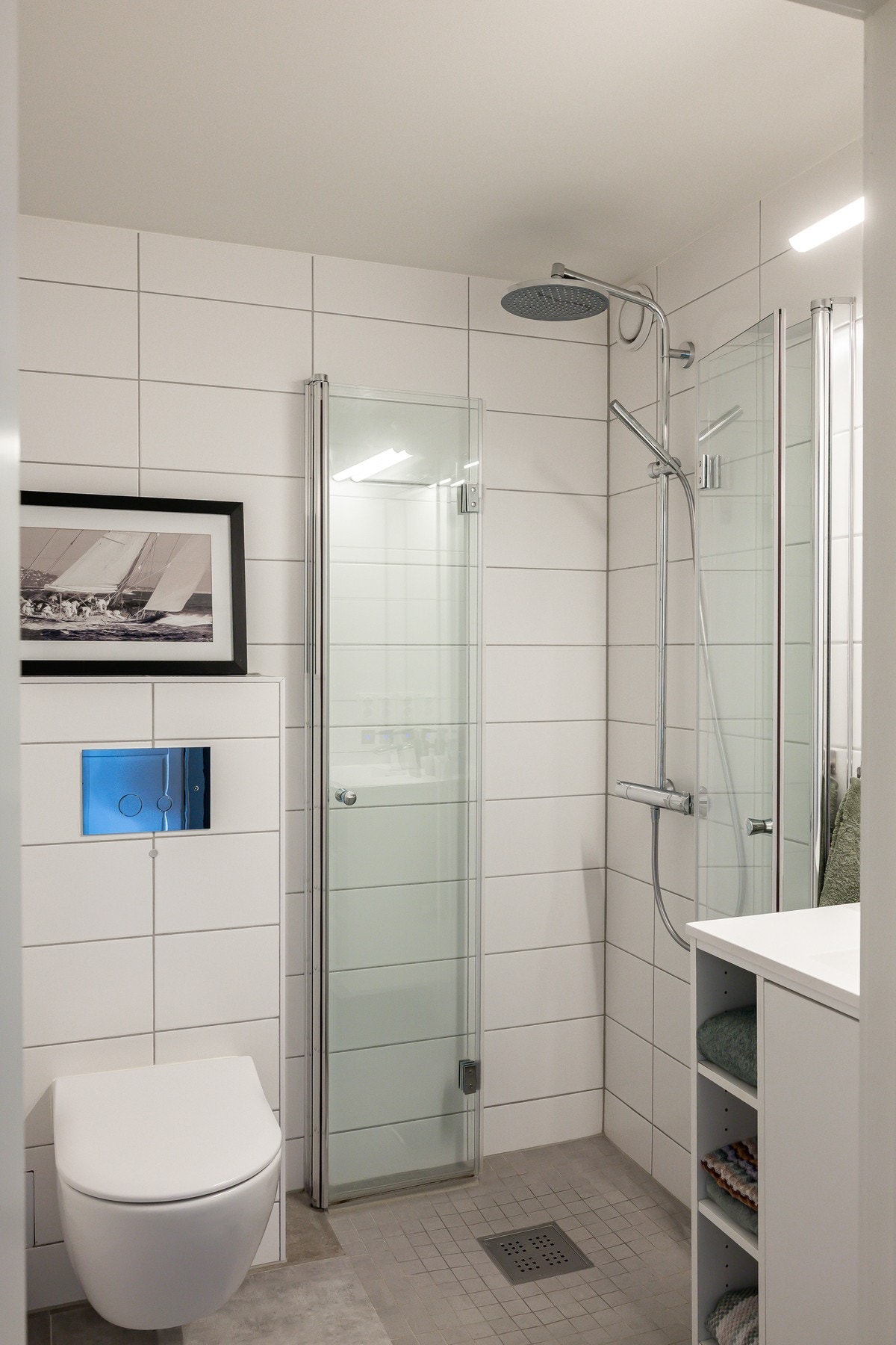 Det andre badet med adkomst fra gang er utstyrt med servant med underskap, speil med belysning, veggmontert toalett og dusjløsning med glassvegg. Galleribilde