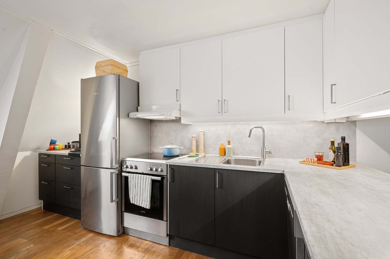 Tidløst kjøkken med kontrast mellom lyse overskap og mørkere underskap som gir et moderne uttrykk. Galleribilde