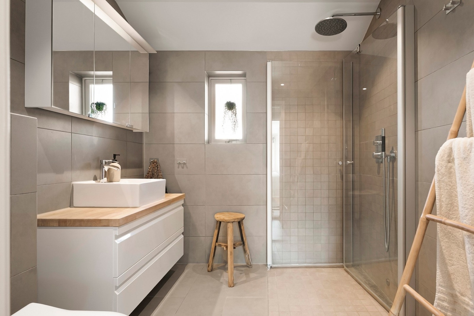 Badet har vegghengt servantinnredning med skuffer og ovenpåliggende servant, samt speilskap med belysning på vegg over servant. Galleribilde