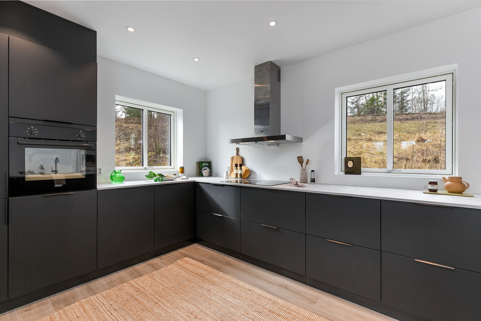 Stilrent kjøkken i åpen løsning mot stuen, utformet i en praktisk vinkelløsning med godt med skap- og benkeplass. Galleribilde