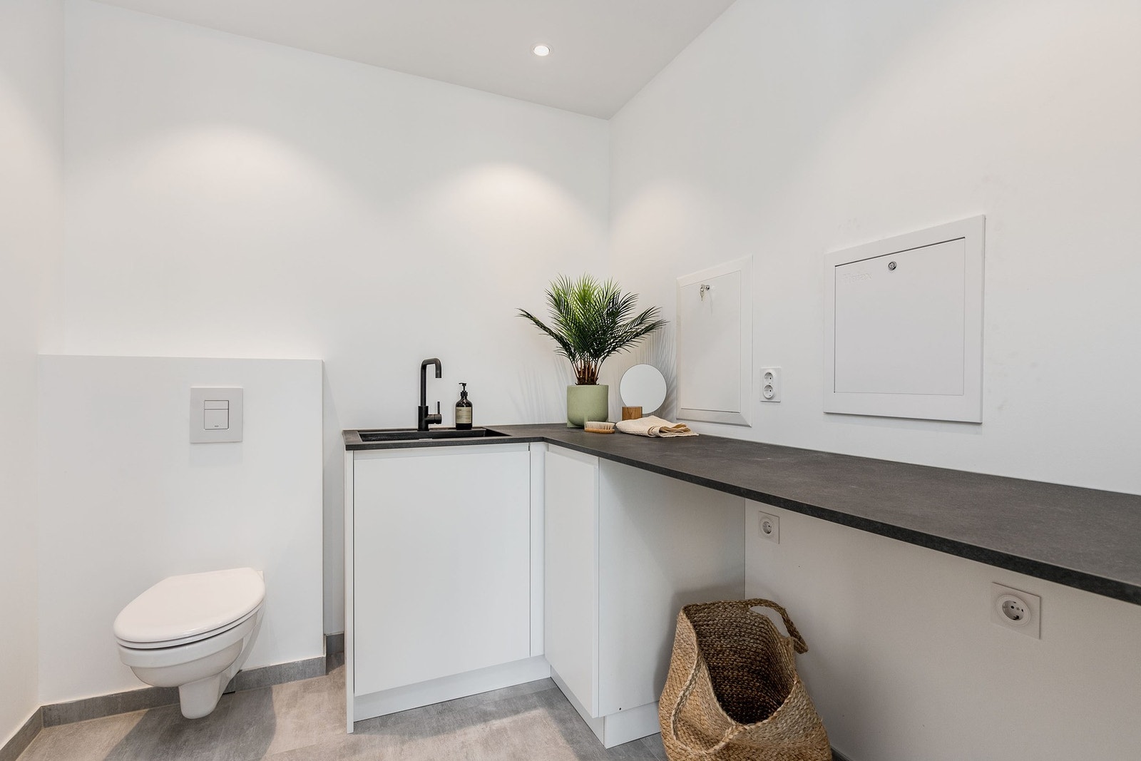 Seksjonert utleiedel: Praktisk vaskerom med benkeinnredning, skap, utslagskum og opplegg for vaskemaskin og tørketrommel under benk, samt vegghengt toalett. Galleribilde