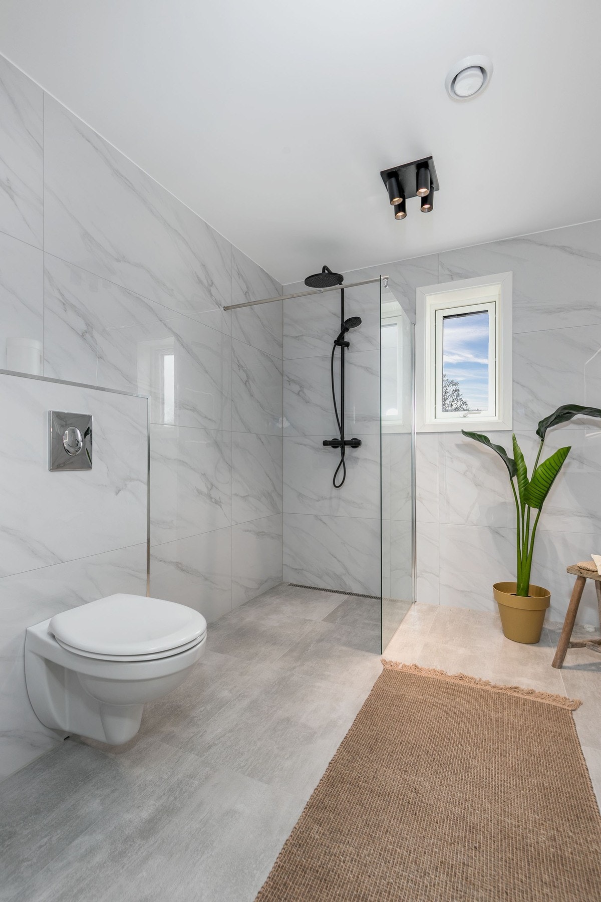 Videre har badet et vegghengt toalett og dusjhjørne med regnfallsdusj. Galleribilde