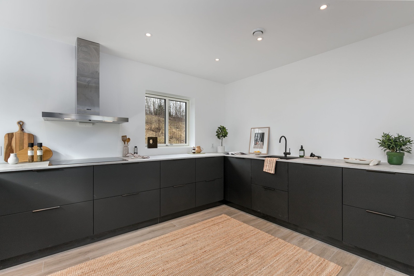 Innredningen har slette fronter i sort utførelse og laminert benkeplate i lys utførelse. Integrerte hvitevarer inkluderer induksjonstopp, stekeovn, oppvaskmaskin og kombinert kjøle-/fryseskap. Galleribilde