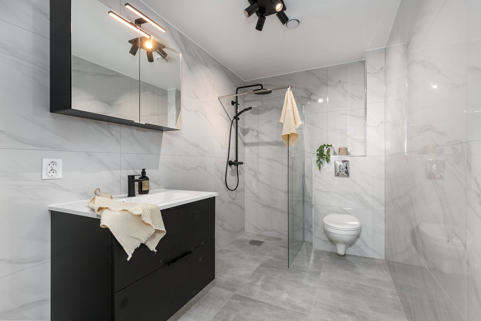 Bad nr. 2 i boligens 2. etasje har flislagte overflater og varmekabler i gulv. Innredningen består av servantmøblement, speilskap, vegghengt toalett, samt separat dusjhjørne med glassvegg og regnfallsdusj. Galleribilde