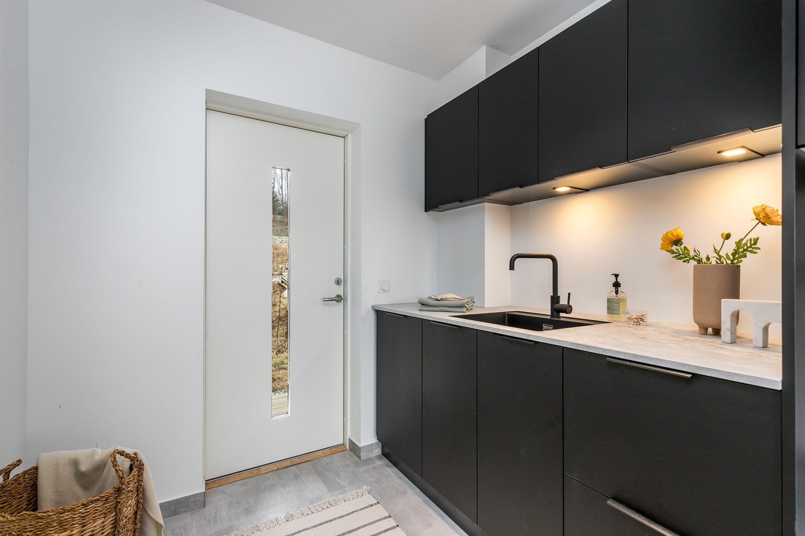 Praktisk vaskerom med benkeinnredning, skap, utslagskum og opplegg for vaskemaskin og tørketrommel. Galleribilde