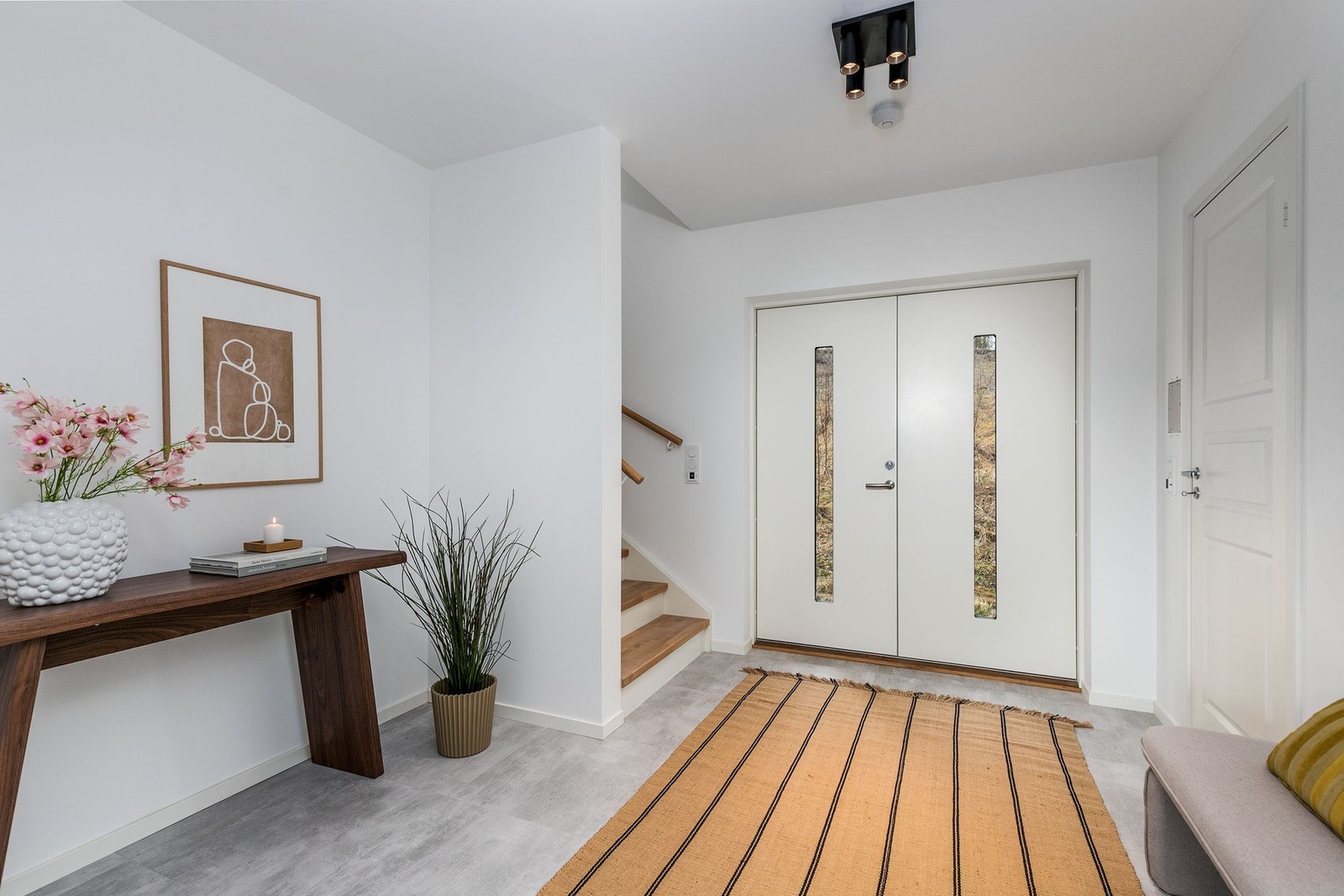 Lys og innbydende hall med storformatfliser, gulvvarme og malte slette vegger som gir et godt førsteinntrykk. Dobbel inngangsdør - ideelt for en familie. Galleribilde