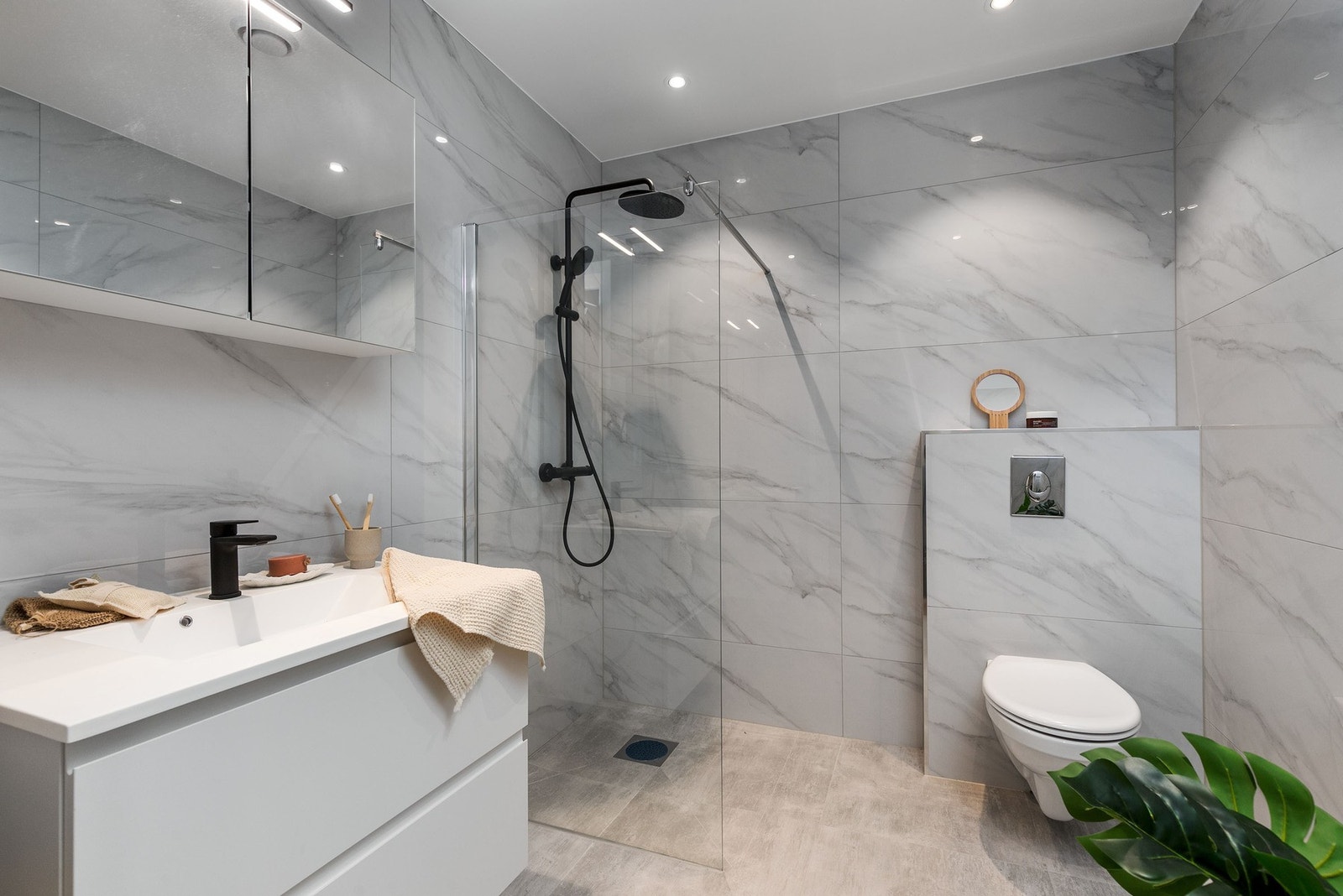 Seksjonert utleiedel: Delikat flislagt bad med gulvvarme, servantmøbel, speilskap, vegghengt toalett og dusjhjørne med glassvegg og regnfallsdusj. Galleribilde