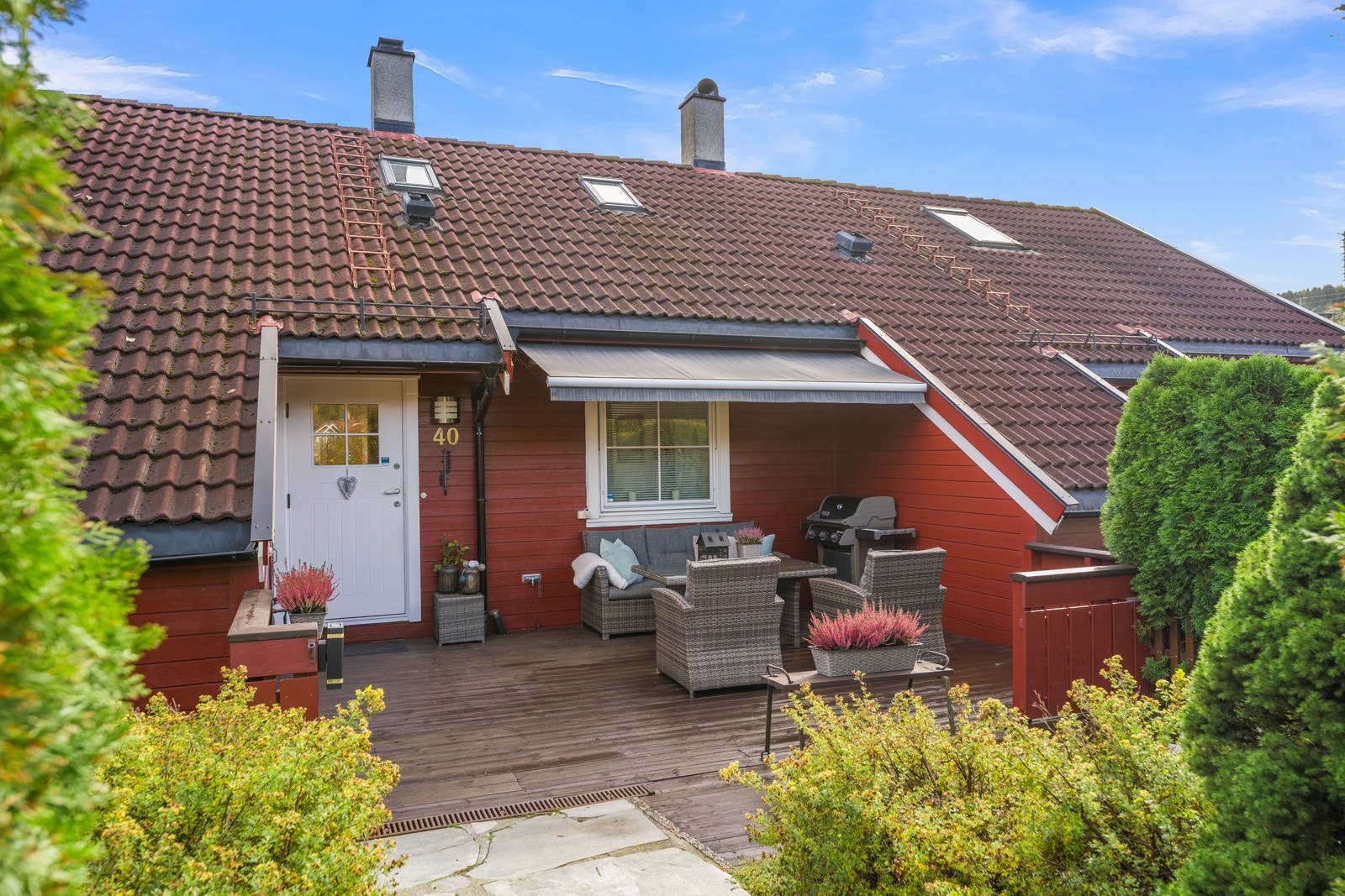 Solrik og skjermest uteplass ved inngangen til boligen. Markise. Utebod helt til venstre i bildet. Galleribilde