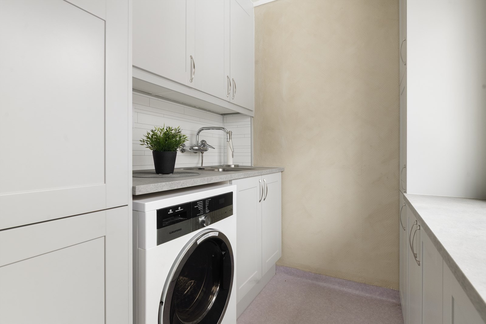 Vaskerommet innehar skapinnredning og benk med nedfelt vask, opplegg for vaskemaskin og innebygd fryser. Fra vaskerommet er det utgang til en fin terrasse. Galleribilde