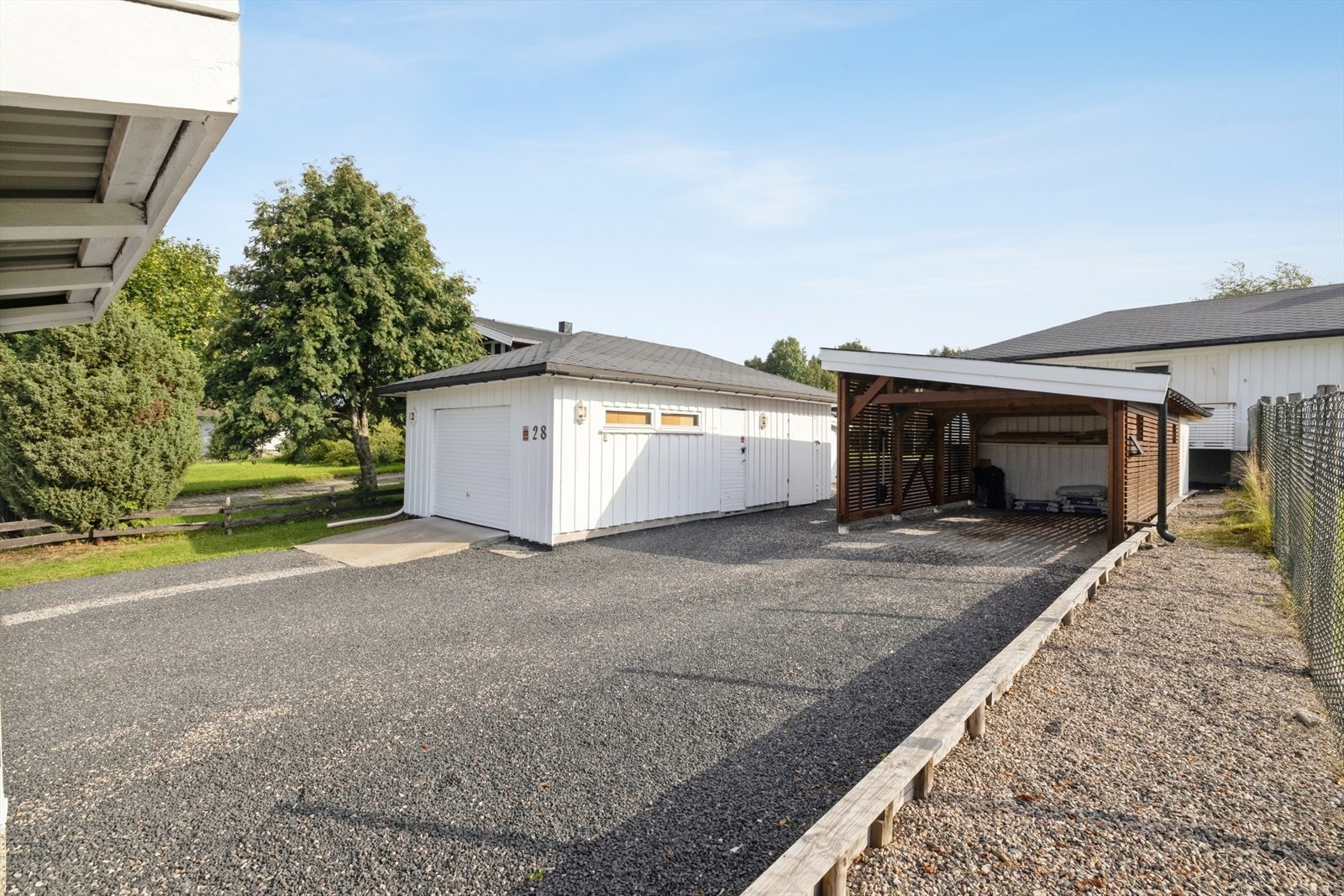 Gruset innkjørsel med god plass til biloppstilling foran garasje og carport. Galleribilde